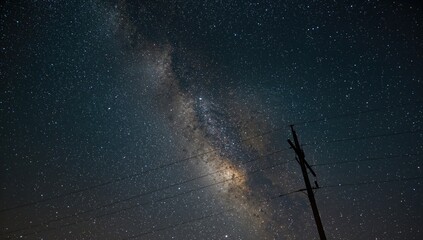 Silhouette of power lines and towers under a starry night sky, energy infrastructure, seasonal change