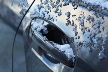 Frozen Car Door Handle Covered with Melting Snow and Ice on a Cold Day