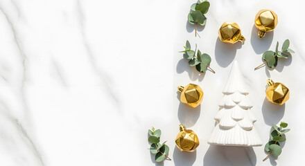 Elegant Christmas flat lay composition with a white ceramic tree, golden ornaments, and eucalyptus on a marble background with copy space