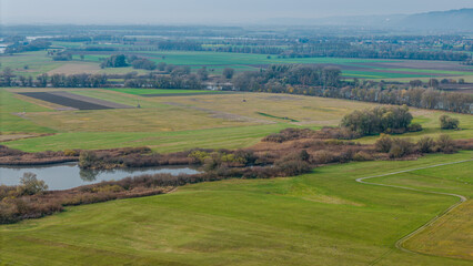 Weite Landschaft mit Wiesen, einem Fluss und landwirtschaftlichen Feldern im Herbst