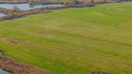 Weite grüne Wiese am Fluss mit sanften Hügeln und ruhigem Wasser an einem klaren Tag