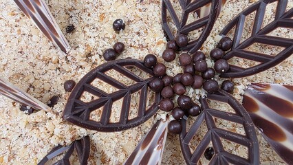 Chocolate cake decorated with sweet snacks, sprinkled with ground nuts, delicious dessert, closeup view from top