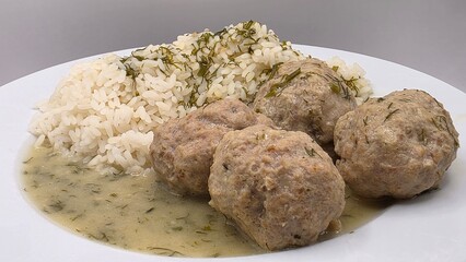 Cooked meatballs with sauce and rice on a plate closeup. Traditional Polish dinner, European cuisine