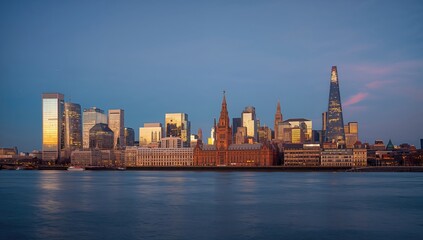 Fototapeta premium City skyline illuminated at twilight with the River Thames visible in the foreground, urban density