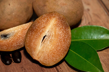 Fresh organic chemical-free sapodilla (Manilkara zapota) sweet and taste fruit with green leaf on wooden background
