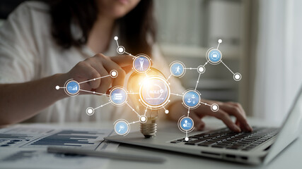 A professional explores creative business strategies using digital tools, symbolized by a light bulb and network connections, while working on a laptop in a modern office setting. Tessel