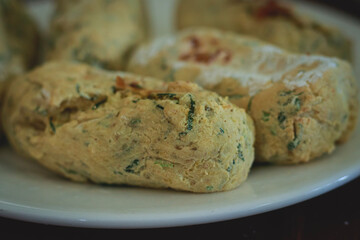 Close-up of savory dough with herbs on a plate and ready to be baked, candid moment of home life and slow living