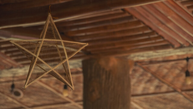 Bamboo made Filipino traditional star Christmas lantern or Parol hangs against a rustic wooden ceiling, creating a cozy aesthetic