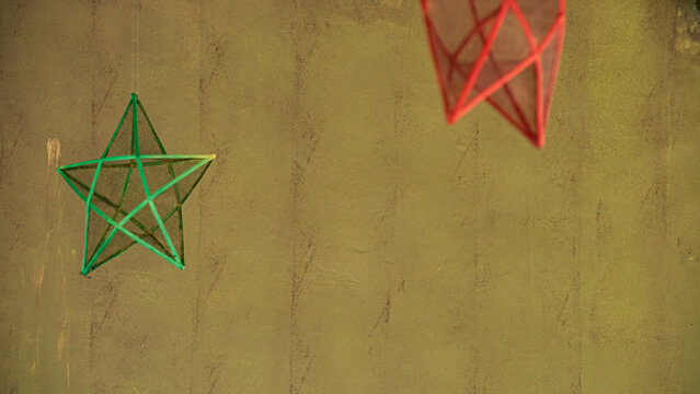 Colorful Filipino traditional star Christmas lantern or parol decorations on a textured wall, creating a simple, artistic contrast
