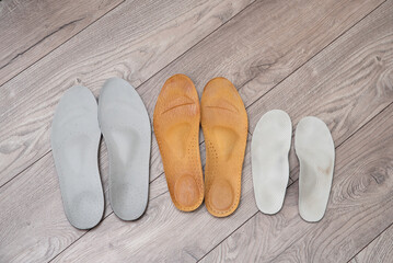 Family orthopedic insoles for adults and a child lying on the home floor and in shoes for valgus prevention and foot health