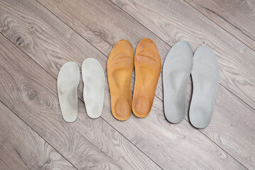 Orthopedic insoles for adults and a child on home floor and in shoes illustrating family concept of foot health and valgus prevention