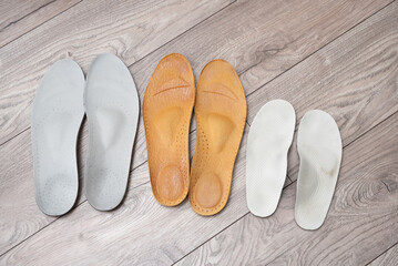 Orthopedic insoles for adults and a child on home floor and in shoes illustrating family concept of foot health and valgus prevention