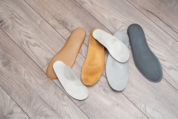 Adult and children orthopedic insoles on the room floor and in footwear showing family foot care and early valgus prevention