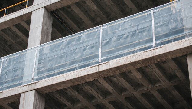 Close-up of a safety cover sheet at a construction site, highlighting modern architectural features and concrete materials, with a focus on innovative elevator technology