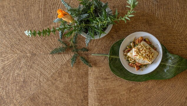 The wooden table features a textured surface resembling leaf veins, enhancing the room's natural ambiance, evoking tropical vibes.
