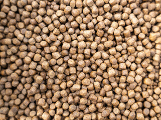 Bulk brown food pellets of different sizes and same form.