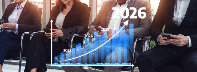 Group of business professionals engaged in analyzing market growth with smartphones, showcasing projected graphs for 2022 to 2026 in a contemporary office setting. Tessel