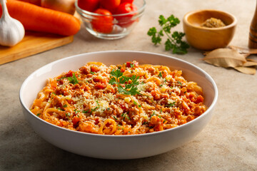 Fettuccine pasta with Ground meat and tomato,spaghetti with a meat based bolognese tomatoes,served on white plate with parmesan cheese.