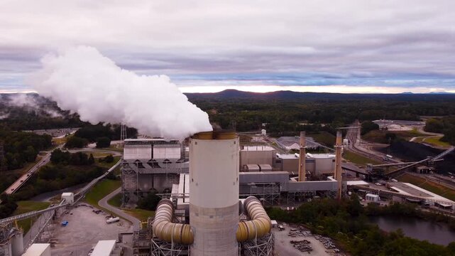Coal power plant in Catawba on Lake Norman emits steam into a colorful sunset sky, aerial cinematic video.