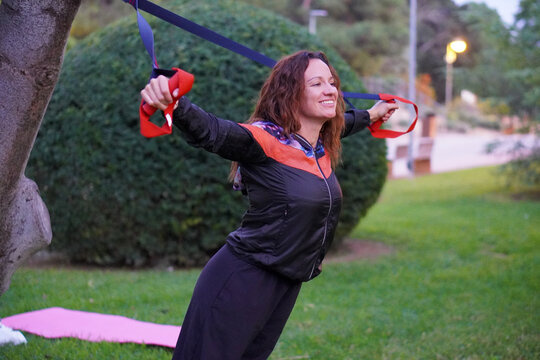 woman, health, and wellness middle-aged woman exercising with a suspension trainer in a park