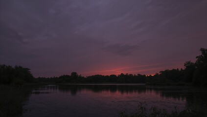 Dark evening sky above a tranquil lake, with soft purple and orange hues at the horizon, enhancing a serene ambiance.