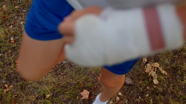 close-up caucasian teen feet and bandaged hand adjusting sock and sandals while practicing steady steps