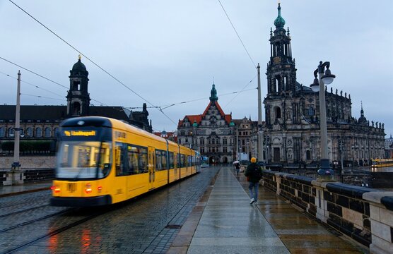 City skyline of Dresden old town on a gloomy rainy day with a tram dashing on Augustus Bridge over Elbe River, and Dresden Cathedral amid the historic buildings in background, in Saxony, Germany