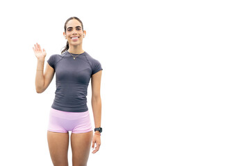 Young woman smiling at camera, waving hand, wearing sportswear and wireless earbuds