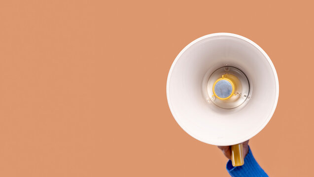 Person holds a megaphone against a plain background to convey a message