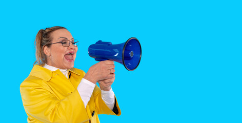Cheerful woman in yellow coat using a megaphone with vibrant blue background
