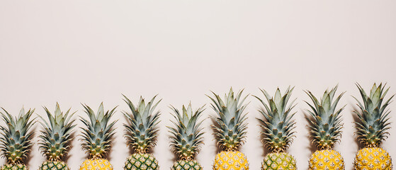 A neat row of fresh pineapples lined up against a minimal background