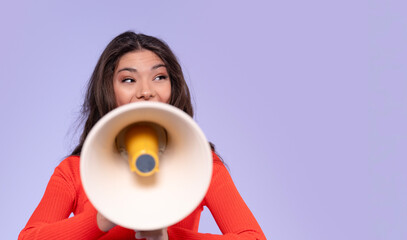 Young woman speaks energetically through a megaphone during a vibrant event