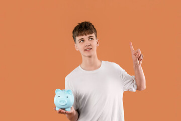 Young boy holds blue piggy bank and thinks about saving money