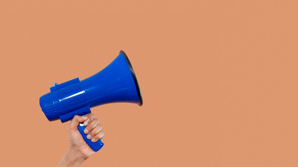 Blue megaphone held in hand against a simple background
