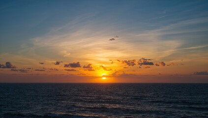 Obraz premium Hued clouds create a vivid sunset over the ocean horizon, seasonal change