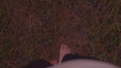 white person barefoot night walk across damp grass shadowed toes slow steps reflective mood low light natural