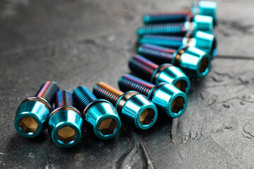 Titanium screws in a row with a hexagon head on a black textured background close-up