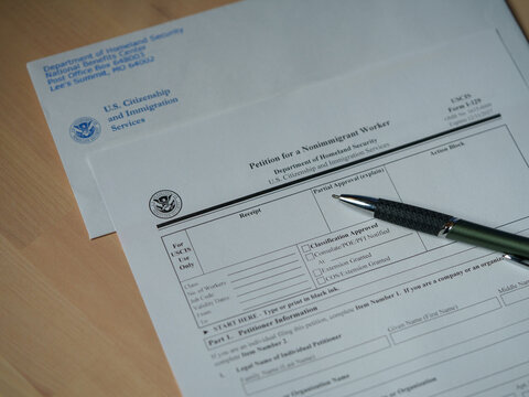 Washington, DC, USA - November, 15, 2025 - Mock USCIS Form I-129 Nonimmigrant Visa Petition for an H-1 worker placed with an official-style envelope and a pen. 