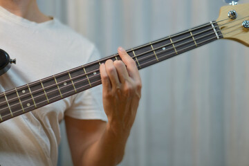 Close-up of hand fretting notes on an electric bass guitar