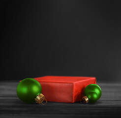 Red pedestal with green Christmas balls on a black background