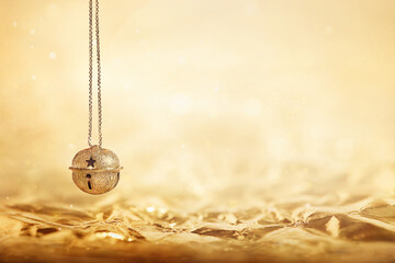 Christmas golden bell is suspended on a golden background of crumpled gold foil,  copy space