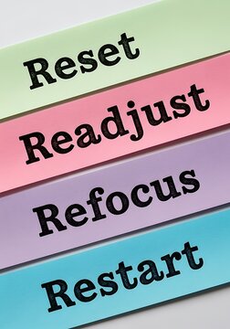 a close up view of stacked colorful plastic strips displaying words like reset readjust refocus and restart suggesting change and adaptation