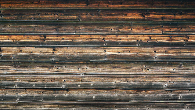 Dark weathered wooden planks laid horizontally, displaying uneven surface and subtle cracks. Rustic vintage concept