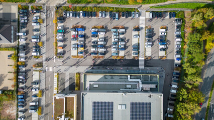Aerial view of a busy parking lot filled with various vehicles, showcasing organized rows of cars...