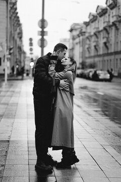 Couple shares a romantic moment on a rainy city street during an overcast day