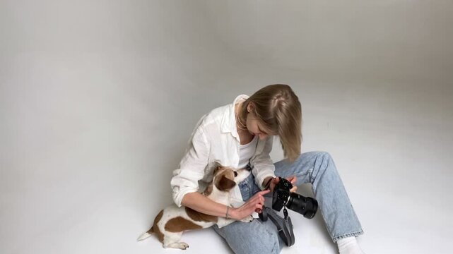 woman and dog Jack Russell terrier Maya look at photo together from camera. dog kissing hugging. tenderness and love of pet. professional photographer in studio with a white cyclorama. video footage