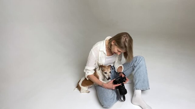 photographer woman woman and dog Jack Russell terrier Maya in studio look at photo together from camera. dog petting care hugging. tenderness and love of pet.   with a white cyclorama. video footage