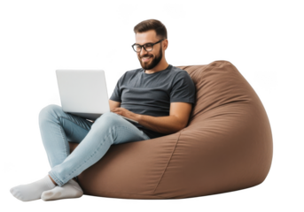 Young man with beard wearing glasses and casual clothes sitting on a large brown beanbag chair using a laptop isolated on transparent background