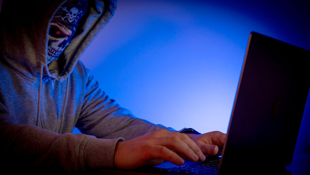 Hacker behind a masked laptop