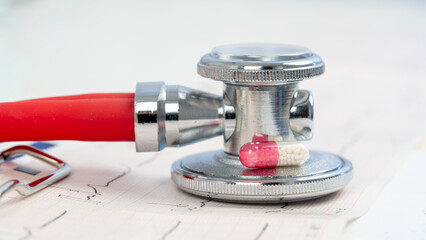 Red pill or vitamin on a cardiogram of the heart